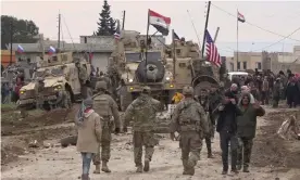  ?? Photograph: AP ?? In this frame grab from video, Russian and Syrian military and local civilians gather next to a USn military convoy stuck in the village of Khirbet Ammu, east of Qamishli city, Syria, on Wednesday.