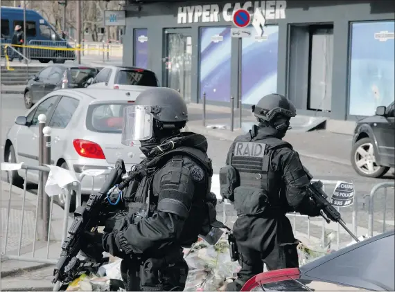  ?? — THE ASSOCIATED PRESS FILES ?? Police officers take position outside the kosher market where four hostages were killed earlier this month.