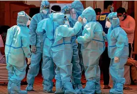  ?? AP ?? Health workers and volunteers in personal protective suits wait to receive patients outside a Covid-19 hospital that was set up at a Sikh gurdwara in New Delhi.