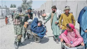  ?? BULENT KILIC AFP VIA GETTY IMAGES FILE PHOTO ?? Afghans carry belongings across the Afghanista­n border to Pakistan at Spin Boldak in September. The U.S. and the Taliban have held their first direct talks since U.S. troops withdrew in August.