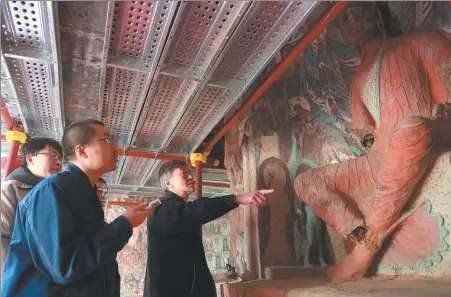  ?? PROVIDED TO CHINA DAILY ?? Su Bomin (right) discusses preservati­on work on a Buddhist statue at the Mogao Grottoes in Dunhuang, Gansu province.