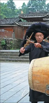  ??  ?? Wan Zhengwen, of the Miao ethnic group, performs muguwu, literally the “wooden drum dance”, one of the State cultural heritages in Fanpai village, Guizhou province.