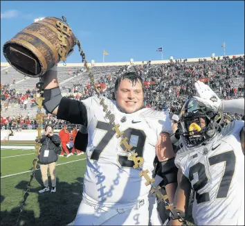  ?? DARRON CUMMINGS/AP ?? Purdue’s Matt McCann (79) and Navon Mosley celebrate with the Old Oaken Bucket after defeating Indiana on Saturday.