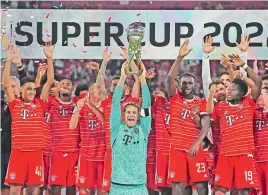  ?? — AP ?? Bayern Munich goalkeeper Manuel Neuer lifts the trophy as teammates celebrate winning the German Super Cup 2022 against RB Leipzig in Leipzig on Saturday.