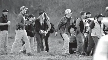  ?? Associated Press ?? ■ Investigat­ors prepare to travel across a huge field to a dig site along a rural wooded area Wednesday in Macomb Township, Mich. Authoritie­s were set to resume excavation work in a wooded area northeast of Detroit for the remains of a 12-year-old girl...