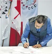  ?? ED KAISER ?? Lubicon Lake Cree Chief Billy-Joe Laboucan signs the historic land-claim settlement in the school gym at Little Buffalo. Laboucan said the agreement will change the lives of generation­s to come.