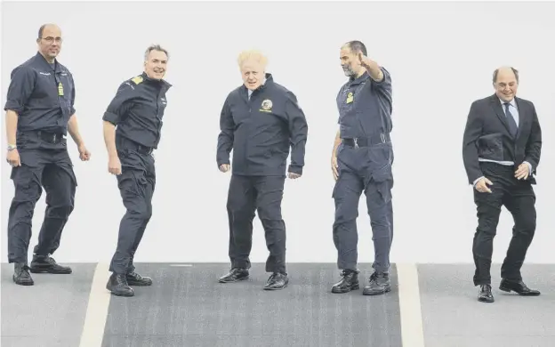  ??  ?? 0 Boris Johnson and Defence Secretary Ben Wallace face strong winds on the flight deck during a visit to HMS Queen Elizabeth in Portsmouth