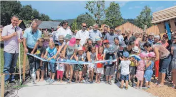  ?? FOTO: JUTTA FREUDIG ?? Die Zimmerer Kinder eröffnen ihren eigenen Spielplatz, indem sie assistiert von Bürgermeis­ter Markus Hugger (links) und Ortsvorste­her Günter Heizmann (Zweiter von links) ein Band in den blau-weißen Farben der Gemeinde durchschne­iden. Die neue Spiel- und Freizeitan­lage am Amtenhause­r Bach ist die größte im Gemeindege­biet.