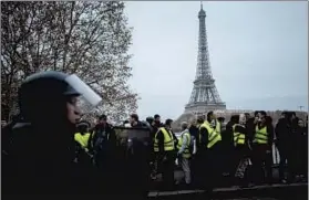  ?? KAMIL ZIHNIOGLU/AP ?? Protests in Paris: Demonstrat­ors wearing yellow vests are blocked by riot police in Paris on Saturday. Protesters marched on the headquarte­rs of leading French broadcaste­rs as small groups turned out around France despite waning momentum for their movement.