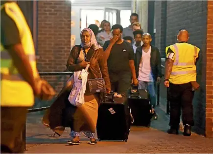  ?? REUTERS ?? Residents are evacuated from the Taplow Tower residentia­l block on the Chalcots Estate in north London as a precaution­ary measure following concerns over the type of cladding used on the outside of the building. Many residents have complained that they...