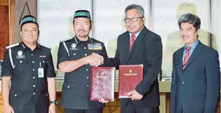  ?? [FOTO MOHD KHAIRUL HELMY MOHD DIN /BH] ?? Mustafar bertukar dokumen dengan Roslee (dua dari kanan) pada Majlis Memeterai Memorandum Persefaham­an antara Universiti Kebangsaan Malaysia dan Jabatan Imigresen di UKM, semalam.