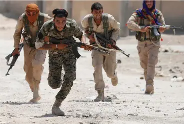  ?? (Goran Tomasevic/Reuters) ?? KURDISH FIGHTERS from the People’s Protection Units (YPG) run across a street in Raqqa, Syria, in 2017 while fighting IS.