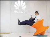  ?? ?? A man wearing a mask to curb the spread of the coronaviru­s sits near a Huawei store logo in Beijing on Friday, July 31, 2020. (AP)