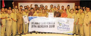  ?? CHUSNUL CAHYADI/JAWA POS ?? AYO MAJU: Tursilowan­to Harijogi (tengah memegang koran) diapit Moh. Qosim (kiri) dan Ivan Firdaus bersama para Kades peserta program Desa Berdaya 2018.