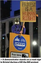  ??  ?? > A demonstrat­or stands on a road sign in Bristol during a Kill the Bill protest