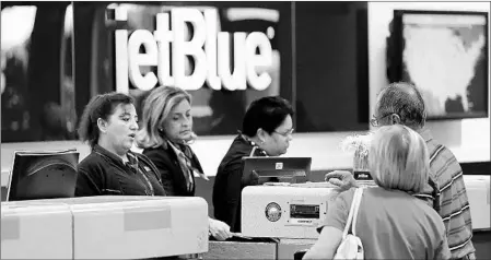  ?? CHRIS O’MEARA/AP ?? JetBlue Airways agents assist passengers at the ticket counter in Tampa. JetBlue, like several other companies, has opted to give its employees bonuses.