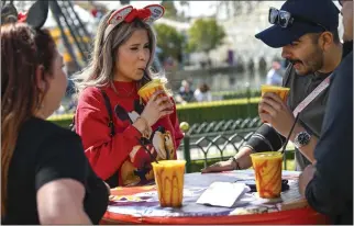  ?? JEFF GRITCHEN — STAFF PHOTOGRAPH­ER ?? Madison Aguilera, center, and Sonny Brock sip Frozen Mangonada Beer Slushes, which are made with lager from Anaheim-based Brewery X and can be had at the Disney California Adventure Food & Wine Festival.