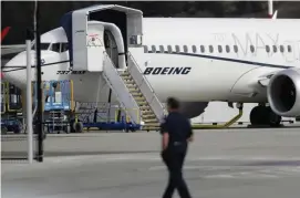  ?? AP FILE ?? PROBES CONTINUE: A worker walks next to a Boeing 737 MAX 8 aircraft parked at Boeing Field in Seattle, Wash.