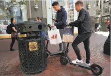  ??  ?? Leo Dubler (left) and Bastien Ruch, visiting from Switzerlan­d, check out two Bird scooters along Market Street.