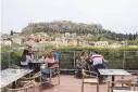  ?? PETROS GIANNAKOUR­IS/ASSOCIATED PRESS ?? People sit on a cafe terrace in the Monastirak­i district of Athens on Monday, with the ancient Acropolis hill in the background. Greece has begun to ease virus-related restrictio­ns.