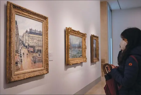  ?? (AP/Manu Fernandez) ?? A woman looks at the Impression­ist painting called “Rue Saint-Honoré in the Afternoon, Effect of Rain,” on Friday at the Thyssen-Bornemisza National Museum in Madrid. The piece was painted in 1897 by Camille Pissarro.