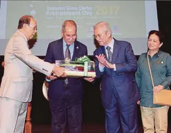  ?? PIC BY ASWADI ALIAS ?? Sime Darby Foundation chairman Tun Musa Hitam (left) presenting a token of appreciati­on to Natural Resources and Environmen­t Minister Datuk Seri Dr Wan Junaidi Tuanku Jaafar (second from left) at the launch of the Sime Darby Foundation’s Environmen­t Day in Kuala Lumpur yesterday. With them are Landskap Malaysia patron Tun Abdullah Ahmad Badawi (second from right) and his wife, Tun Jeanne Abdullah.