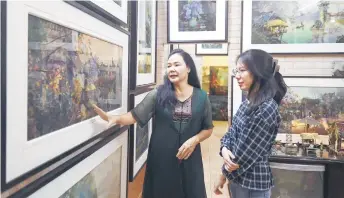  ?? ?? Thuc (le ) talking to a visitor about her artworks made from fabrics in her home studio in Hanoi.