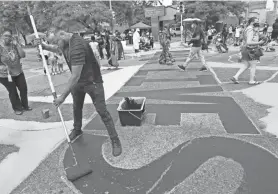  ?? MICHAEL SEARS / MILWAUKEE JOURNAL SENTINEL ?? Vedale Hill, lead artist on the project, works on the large black letters in the center of the mural. A host of helpers paint other colors and designs around the edges at the intersecti­on of North King Drive and West Locust Street on Friday.