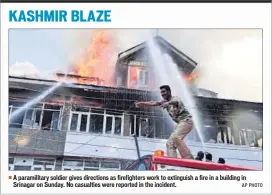  ??  ?? A paramilita­ry soldier gives directions as firefighte­rs work to extinguish a fire in a building in Srinagar on Sunday. No casualties were reported in the incident. AP PHOTO