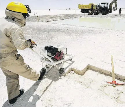  ?? AIZAR RALDES/AFP/GETTY IMAGES FILES ?? A worker cuts salt bricks at the state-run lithium plant at Bolivia’s Uyuni Salt Flats. There are growing fears that the supply and demand forecasts for lithium are out of whack, and that prices will crash, even as massive growth is forecast for the metal.