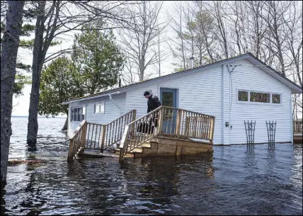  ?? CP PHOTO ?? A man carries a bag of clothing before leaving his home as floodwater­s from the Saint John River continue rising in Grand Lake, N.B. on Wednesday.