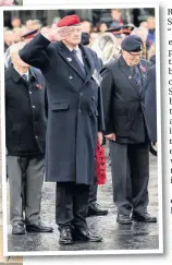  ??  ?? A veteran salutes in silent tribute as, left, a wreath is laid at the Cenotaph