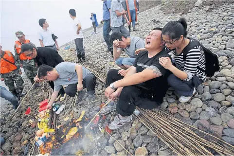  ?? REUTERS ?? Family members of ‘Eastern Star’ cruise ship victims burn offerings as they cry during a ceremony to mark seven days since the ship sank in the Jianli section of Yangtze River, Hubei province, China, on June 7, 2015. As of yesterday, 431 people are...