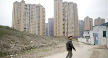  ??  ?? A worker looks back at a constructi­on site next to a newly built residentia­l compound in Wuhan, Hubei province, China.