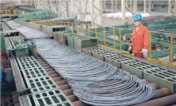  ?? — Reuters ?? A labourer looks at steel coils next to a production line of Dongbei Special Steel Group Co, in Dalian, China.