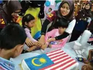  ??  ?? KANAK-KANAK tidak sabar menanti kek Jalur Gemilang dipotong.