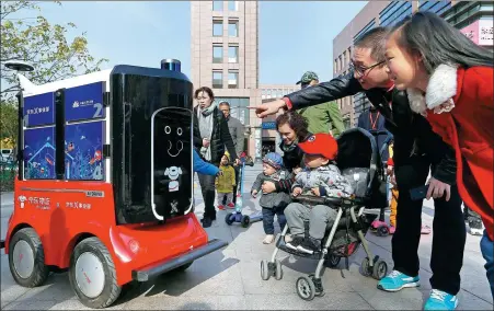  ?? JIA CHENGLONG / FOR CHINA DAILY ?? An artificial intelligen­ce powered delivery robot of JD attracts onlookers in Tianjin.
