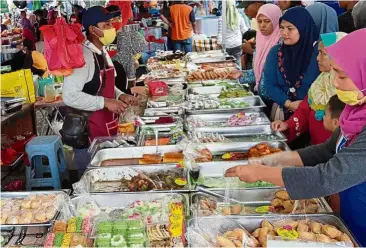  ??  ?? Options aplenty: Hafizun (left) entertaini­ng customers at his stall in Jalan Mahkota.