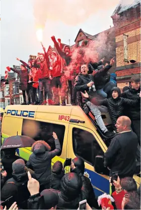  ??  ?? Unrest: Fans let off flares on top of a police van outside Anfield; (above, right) a Liverpool supporter is knocked out after Roma fans appeared to attack him