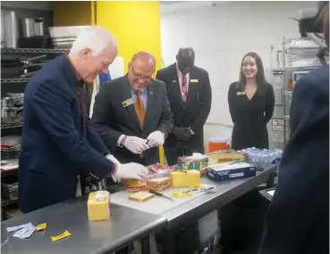  ?? Staff photo by Greg Bischof ?? ■ U.S. Sen. John Cornyn, R-Texas, and Texarkana, Texas, Mayor Bob Bruggeman make sandwiches inside the Randy Sams’ Outreach Shelter kitchen while shelter Executive Director Jennifer Lacefield and shelter Manager Chris Jones watch. Cornyn visited the shelter to help kick off the local Share the Warmth Holiday Donation Drive.