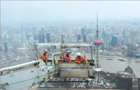  ?? YANG JIANZHENG / FOR CHINA DAILY ?? Workers prepare to clean the walls of the Shanghai World Financial Center on Jan 4, the first working day this year. Their platform often rests 500 meters above the ground.
