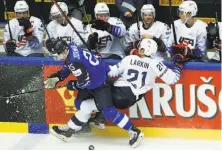  ?? Petr David Josek / Associated Press ?? Finland's Pekka Jormakka (left) checks Dylan Larkin of the U.S. The Americans lost for the first time in seven games.