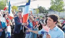  ?? MARC GRANDMAISO­N THE CANADIAN PRESS ?? Justin Trudeau points to Andrew Scheer while walking with the crowd during the celebratio­n of the National Acadian Day in Dieppe, Thursday.