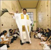  ??  ?? FATHER Chris Bazyouros, of the Archdioces­e of Los Angeles, blesses children and their altars.