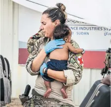  ?? UK MINISTRY OF DEFENCE VIA THE ASSOCIATED PRESS ?? A British army paramedic holds a baby prior to evacuation from Wadi Seidna air base.