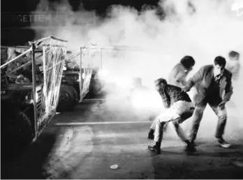  ?? SUN-TIMES FILE PHOTOS ?? LEFT: Soldiers using tear gas and barbed wire strung on jeeps push protesters up Michigan Avenue. RIGHT: A Chicago cop beats a protester on Michigan Avenue in front of the Conrad Hilton Hotel.