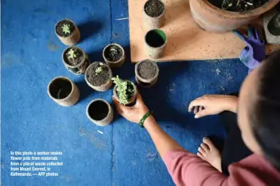  ??  ?? In this photo a worker makes flower pots from materials from a pile of waste collected from Mount Everest, in Kathmandu. — AFP photos