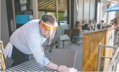  ?? Frank Gun / the canadian pres files ?? Charles Wood wipes down a table on the patio of
Paradiso in Oakville, Ont., on Saturday.