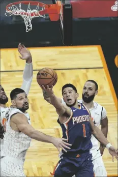  ?? JOHN RAOUX – STAFF, AP ?? PHOENIX SUNS GUARD DEVIN BOOKER (1) misses a shot as he gets between Orlando Magic center Nikola Vucevic (left) and guard Evan Fournier (right) as time expired in the second half of a game Wednesday in Orlando, Fla.