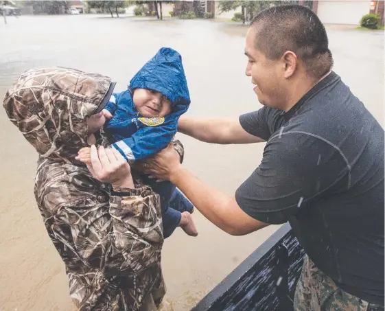  ?? Picture: AP ?? Wilfredo Linares reaches out for his baby, Mason, as they are evacuated from Grand Mission subdivisio­n in Fort Bend county, Texas. The rising floodwater­s from Tropical Storm Harvey have forced the evacuation of thousands of people.